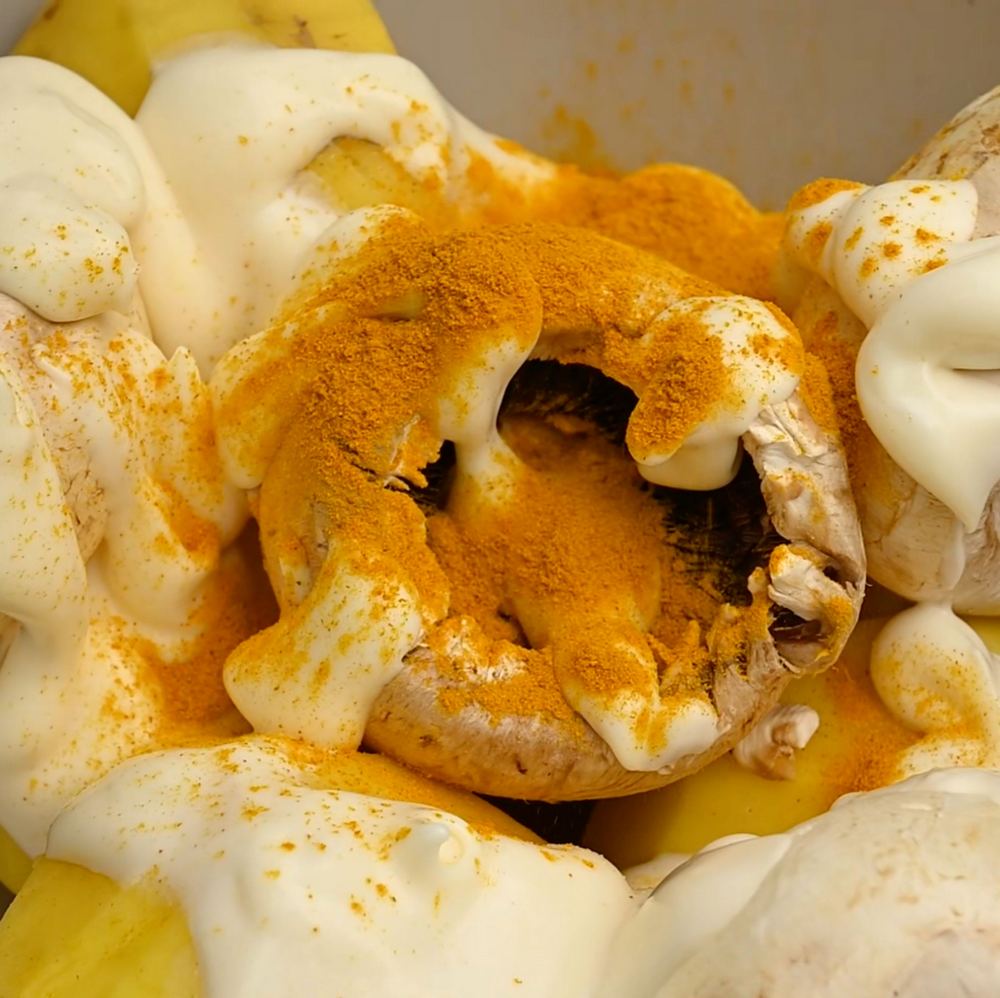 Замаринуйте шампиньоны и картофель в смеси из оливкового майонеза, куркумы, сладкой испанской паприки и микса перцев