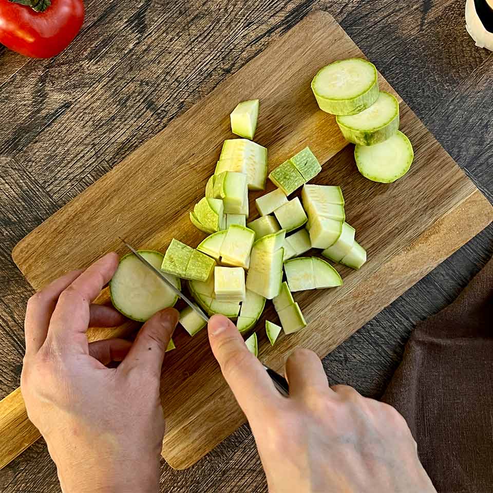 Кабачки и баклажаны нарежьте кубиками, не очищая от кожуры.
Добавьте их тушиться к овощам, посолите и поперчите.