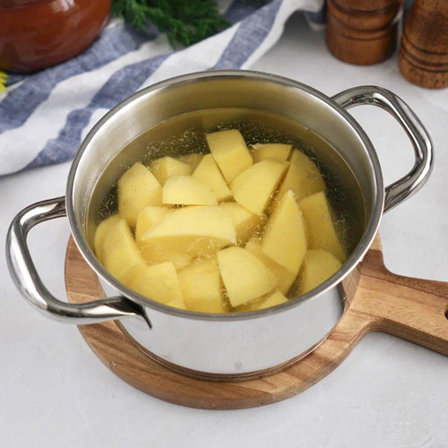 Очистите картофель от кожуры, нарежьте на крупные кубики и отварите в подсоленной воде до готовности — примерно 20 минут.
