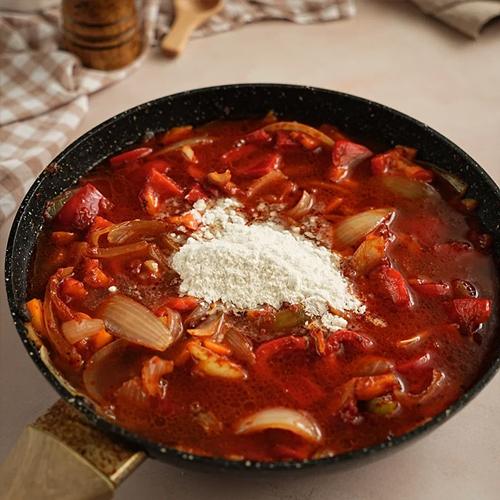 Переложите овощи в казан к мясу. Влейте бульон, посолите и поперчите по вкусу.