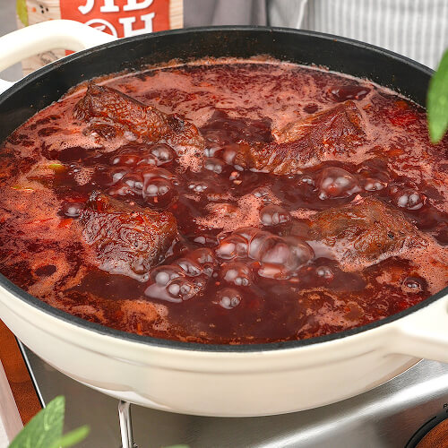 Когда жидкость закипит, накройте сковороду крышкой и оставьте мясо томиться на слабом огне примерно на 3 часа. Ориентируйтесь на текстуру: готовые щёчки должны легко распадаться на волокна. Примерно за полчаса до конца приготовления посолите и поперчите.