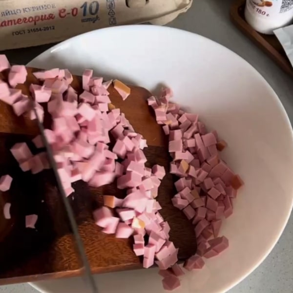 Нарежьте Докторскую колбасу маленькими кубиками.