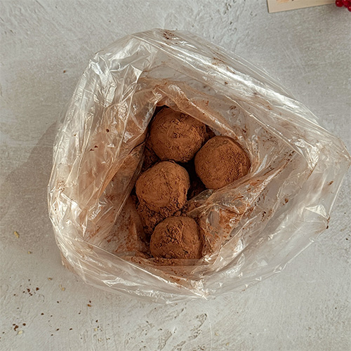 Насыпьте какао в пакет и положите туда же небольшую партию конфет. Обваляйте их в какао.