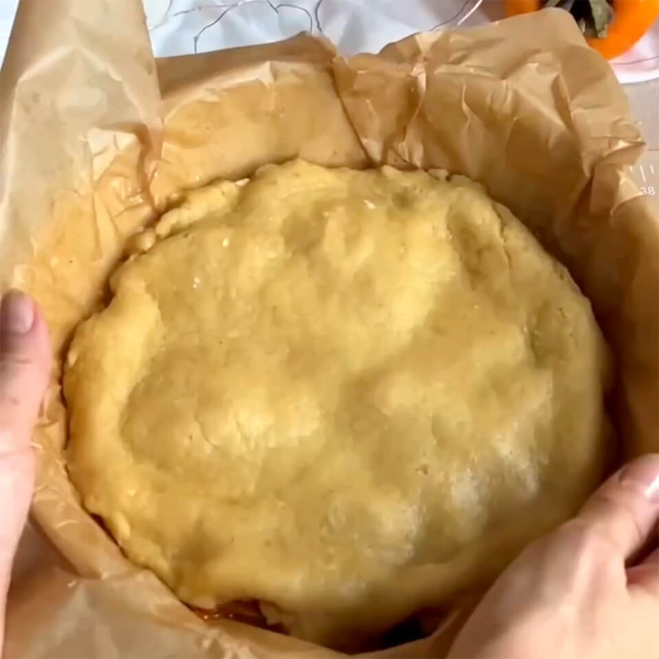 Накройте хурму тестом, приминая края вниз. Проколите в нескольких местах вилкой и отправьте в духовку примерно на 20 минут при 200℃.